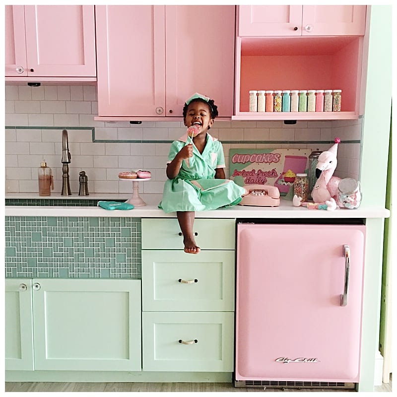 Libby sitting on the counter in the mint and pink kitchenette